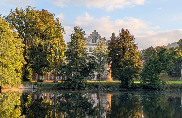 Das Schloss spiegelt sich im See im Park Reinhardsbrunn